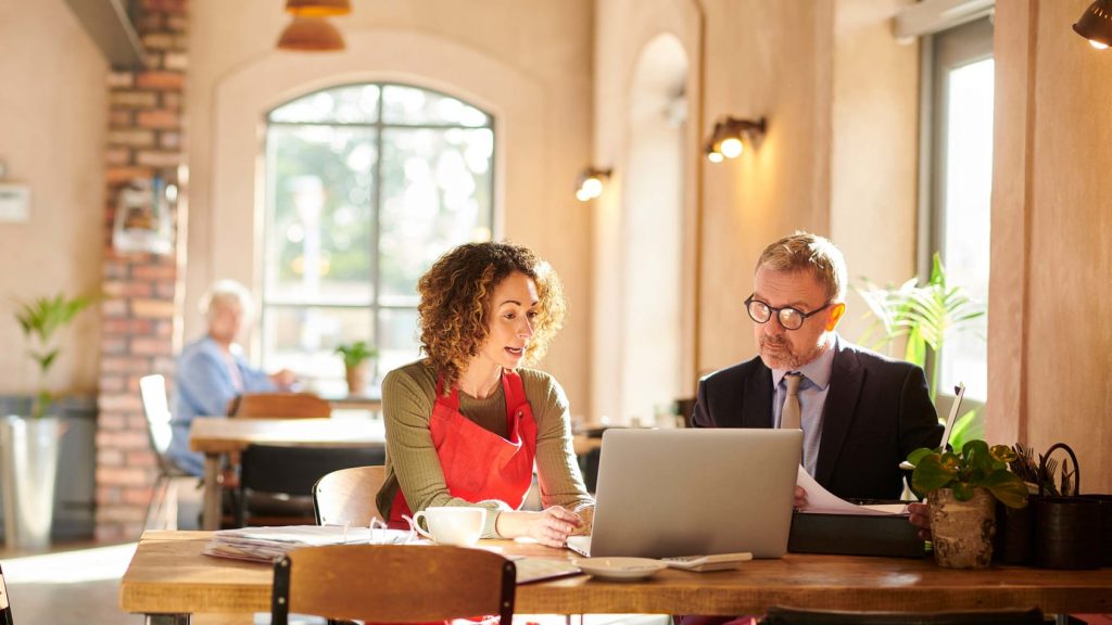 Woman showing a man something on her laptop at a table